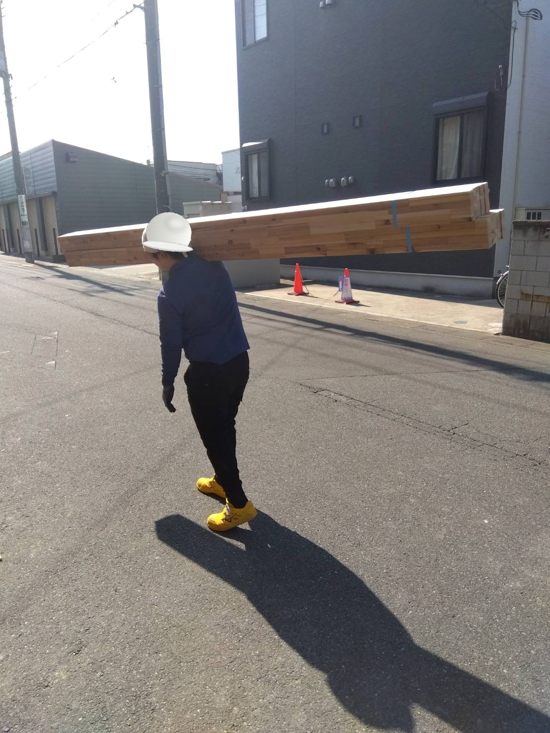 長尺材を担いで運ぶ荷揚げ・揚重の作業員